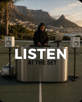 DJ playing behind an AT THE SET steel counter at dusk
