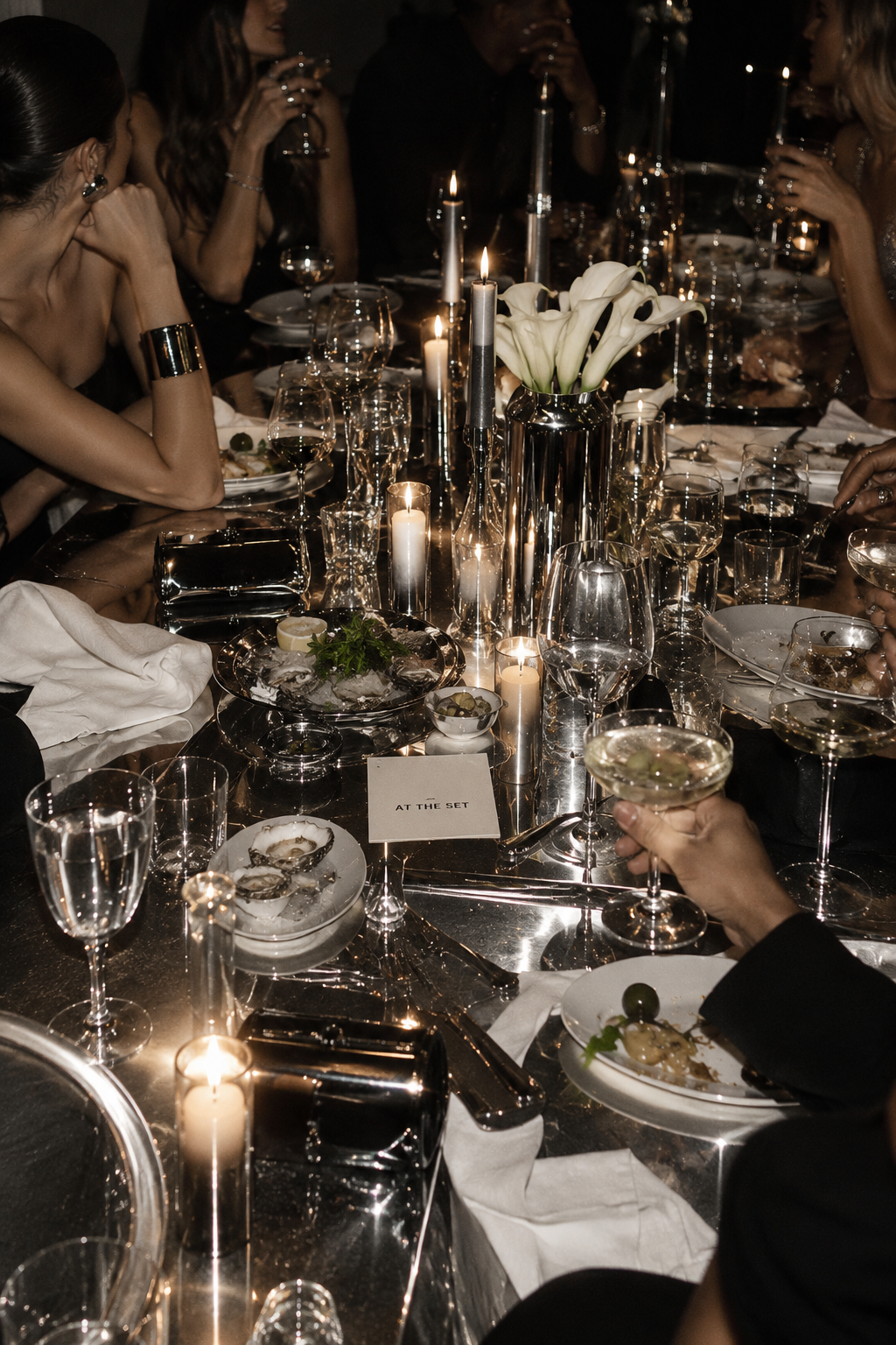 Candlelit dinner table with oysters, cocktails and guests at AT THE SET